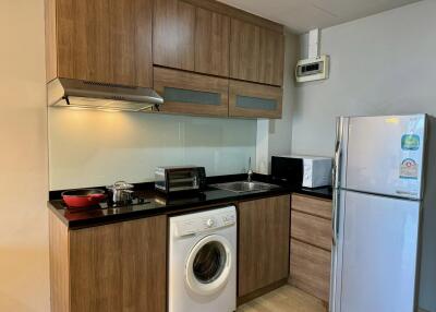 Modern kitchen with wooden cabinets, appliances, and a washing machine