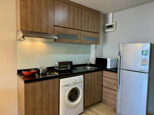 Modern kitchen with wooden cabinets, appliances, and a washing machine