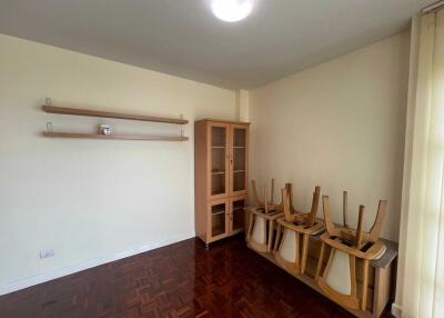 Empty dining area with parquet flooring and furniture stacked on a side table