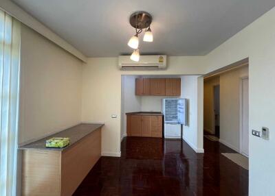 Well-lit kitchen area with wooden cabinets and refrigerator.