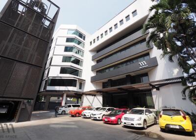 Front view of modern commercial building with parked vehicles