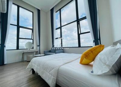 Spacious bedroom with large windows, modern furnishings, and natural light