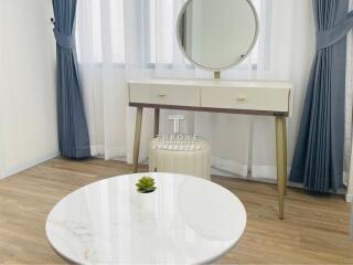 Bright bedroom with vanity table, mirror, and small round table