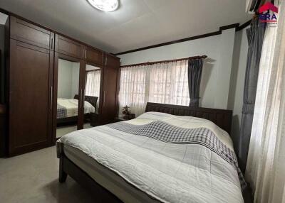 Spacious bedroom with large wardrobe and window drapes