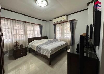 Spacious bedroom with double windows, bedside tables, and a TV