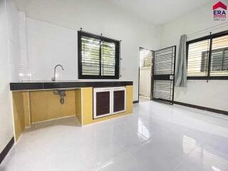 Modern kitchen with white tiles, two black-framed windows, and a simple under-sink cabinet