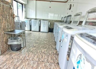 Spacious laundry room with multiple washing machines and drying baskets