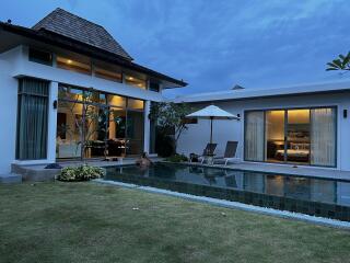 Exterior view of a modern house with a swimming pool and manicured lawn