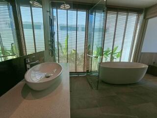 Modern bathroom with large windows, bathtub, and glass shower