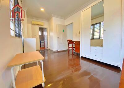 Spacious bedroom with wooden floor, large windows, air conditioning unit, wardrobe, desk, and ample lighting