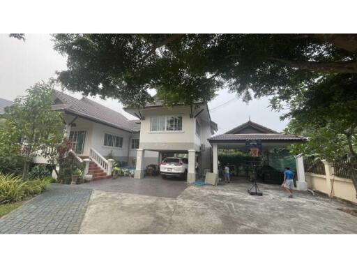 Large two-story house with a driveway, carport, and basketball hoop.