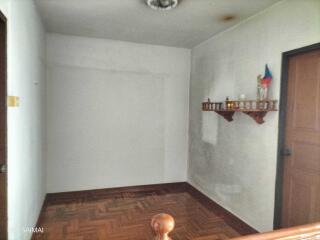 A simple hallway with wooden flooring and a small shelf