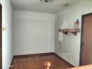 A simple hallway with wooden flooring and a small shelf