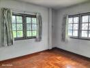 Bright bedroom with hardwood floors and large windows.