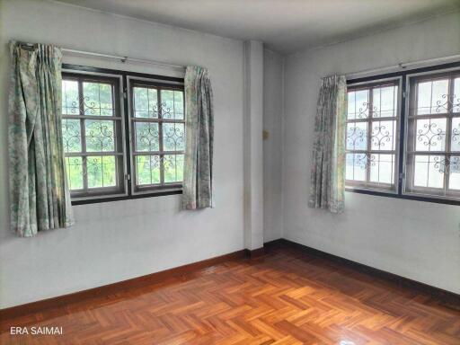 Bright bedroom with hardwood floors and large windows.