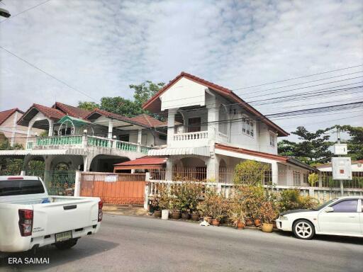 Exterior view of a residential house with a front yard and two vehicles parked on the street