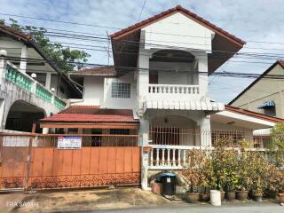 Exterior view of a two-story house with a gated entry and plants in the front yard