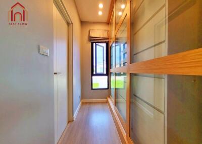 Well-lit hallway with wooden flooring and built-in closets