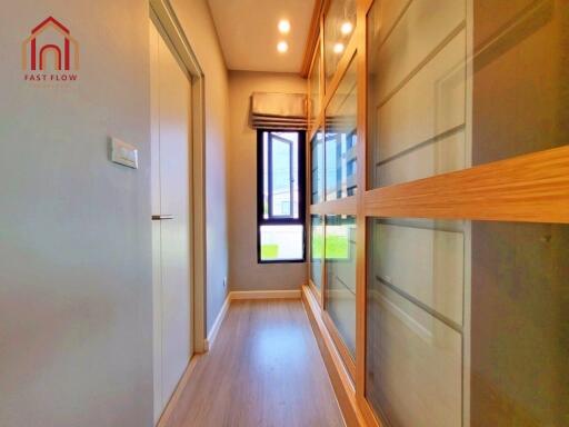 Well-lit hallway with wooden flooring and built-in closets