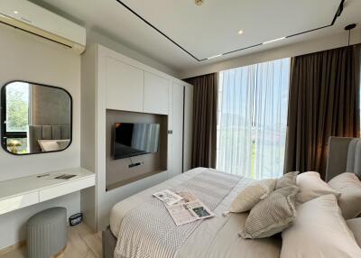 Modern bedroom with a bed, TV, and large window