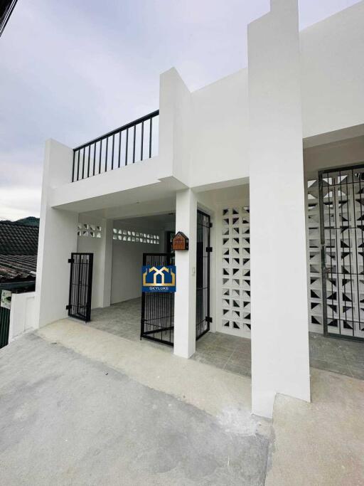 Front view of a modern white building with gated entrance and balcony