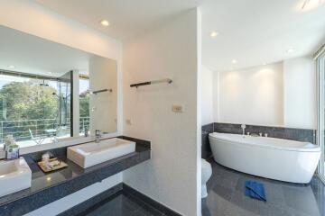 Modern bathroom with double sinks, large mirror, and freestanding bathtub