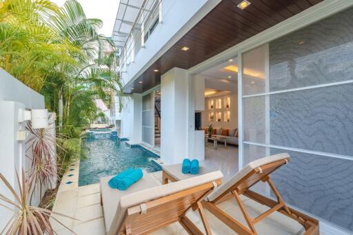 Modern outdoor pool area with loungers and a view into the living space