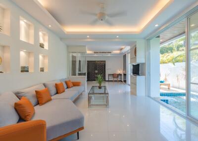 Modern living area with pool access, white walls, and orange accent pillows