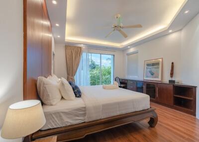 Spacious bedroom with double bed, large window, and wooden flooring