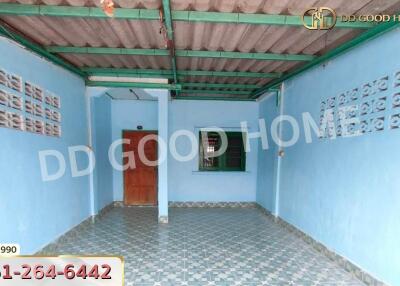 Exterior view of a covered outdoor space with blue walls and patterned floor tiles