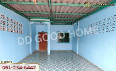 Exterior view of a covered outdoor space with blue walls and patterned floor tiles