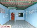 Exterior view of a covered outdoor space with blue walls and patterned floor tiles