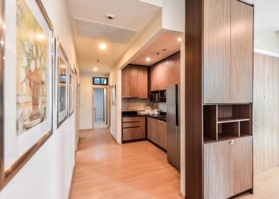 Modern kitchen in an open-plan apartment with wooden cabinets and corridor view