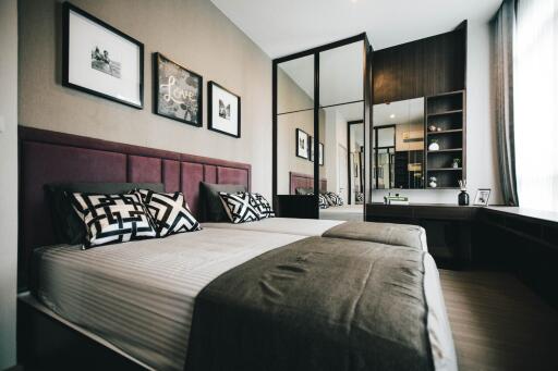 Spacious modern bedroom with a double bed, wall art, large mirror, and desk area