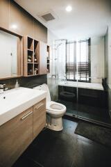 Modern bathroom with glass shower door and wooden cabinets