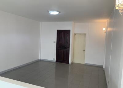 Spacious empty living room with tiled floor and a single light fixture