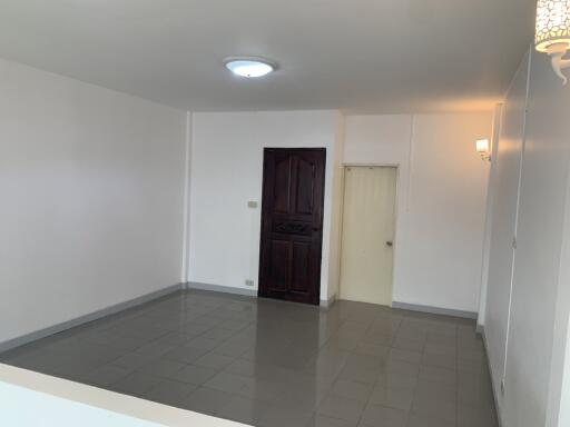 Spacious empty living room with tiled floor and a single light fixture