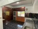 Spacious kitchen with dark tiled flooring and stainless steel sink