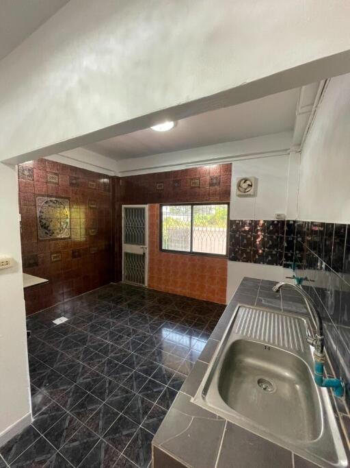 Spacious kitchen with dark tiled flooring and stainless steel sink