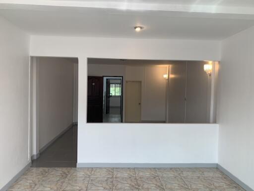 Open living room with tiled floor and partial view of adjacent room