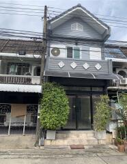 Exterior view of a townhouse with a small balcony and green plants near the entrance