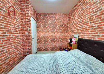 Bedroom with brick walls, white door, and bed with checkered bedding