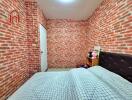 Bedroom with brick walls, white door, and bed with checkered bedding