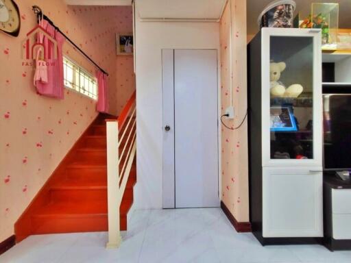 Bright living space with red stairway and storage cabinet