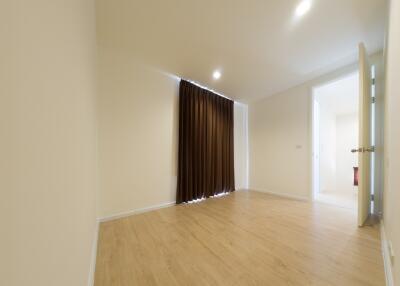 Empty bedroom with wooden floor and closed brown curtains