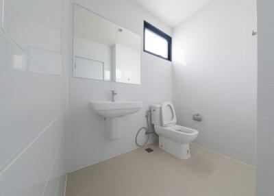 Minimalist white bathroom with sink, toilet, and window