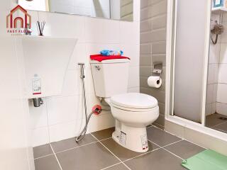 Modern bathroom with white tiles, toilet, shower, and sink