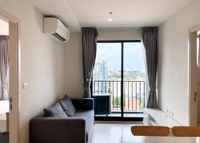 Bright living room with a couch, air conditioning, and large window with a view