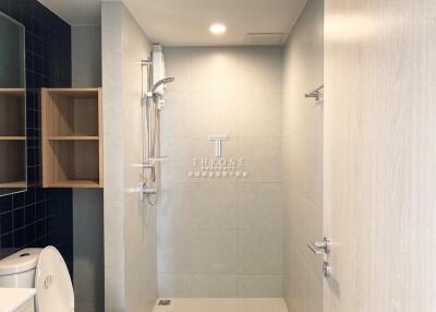 Modern bathroom with shower area, toilet, and storage shelves.