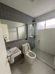 Modern bathroom with glass shower, toilet, and wall-mounted sink